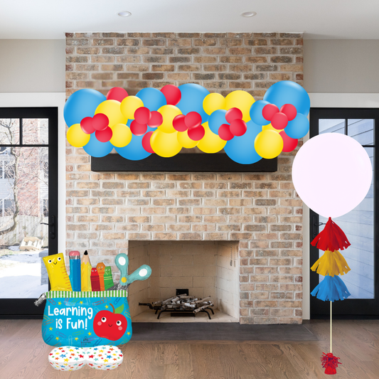 Colorful balloon arch over a fireplace with educational decor items on a wooden floor.