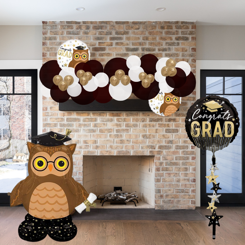 Graduation-themed decorations including owl balloons and 'Congrats Grad' balloons in front of a brick fireplace.